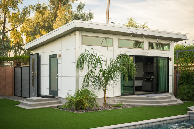 Exterior of a white Studio Home 10x12 Summit ADU with sliding glass doors, landscaped lawn, and pool in Scottsdale, Arizona.